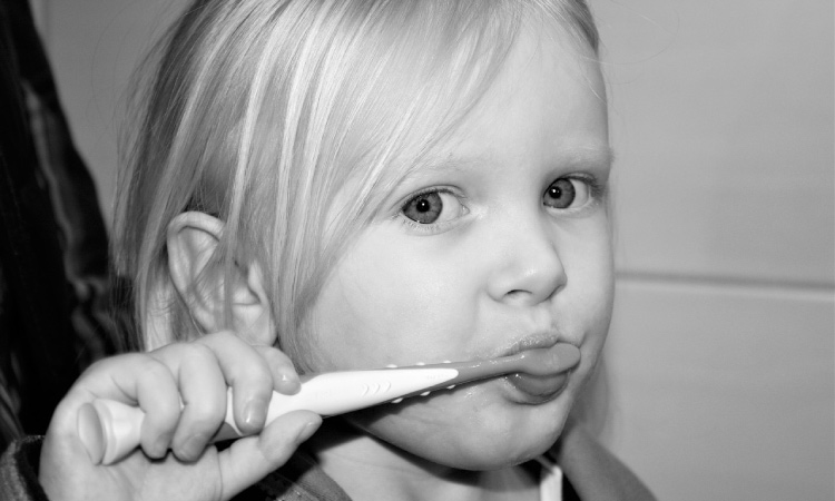young girl brushing her teeth with flouride toothpaste
