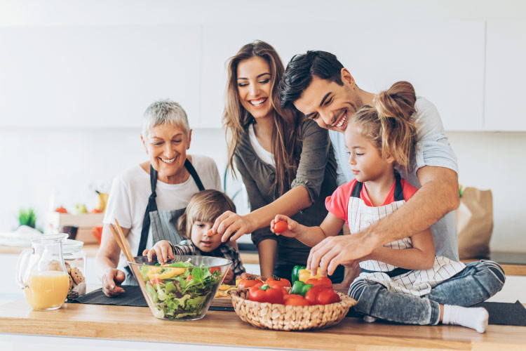 A mom and dad cook dinner with their 2 children and Gramma