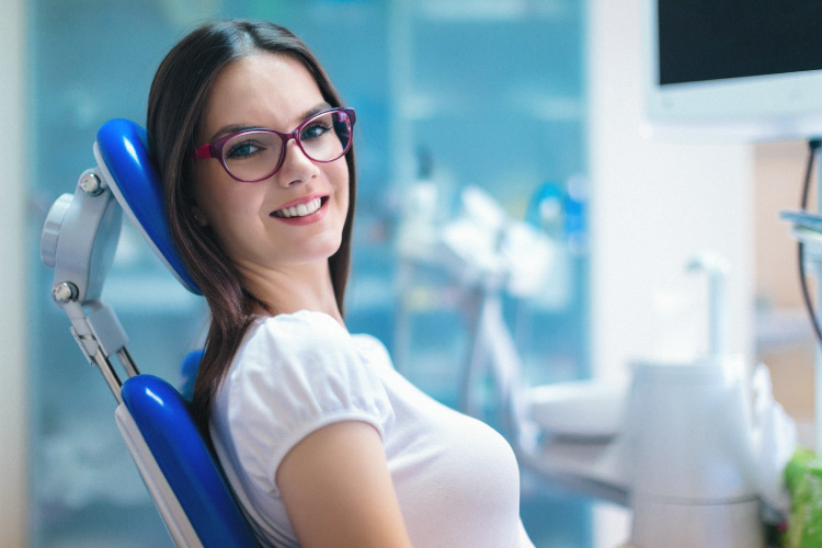 Smiling young adult brunette female in the dental chair ready for root canal therapy