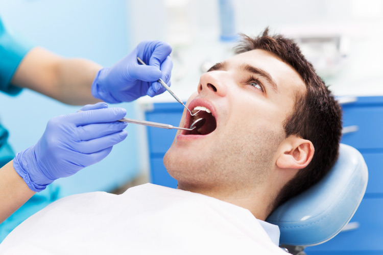 Dark haired young man in dental chair being screened for oral cancer