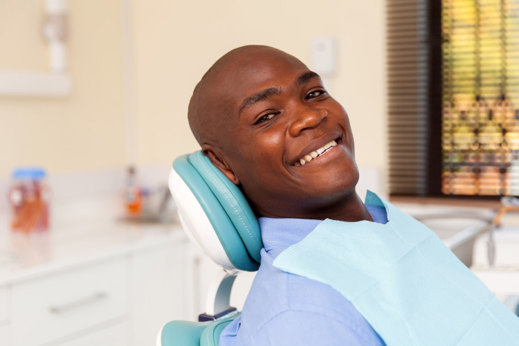 Smiling black man in the dental chair waiting for root canal therapy