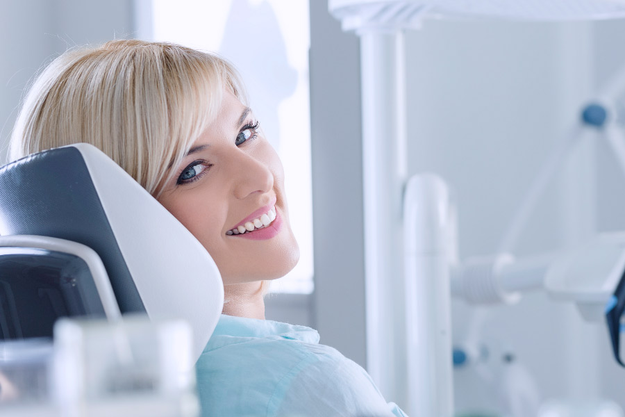 Young blond woman smiling from the dental chair after a deep cleaning.